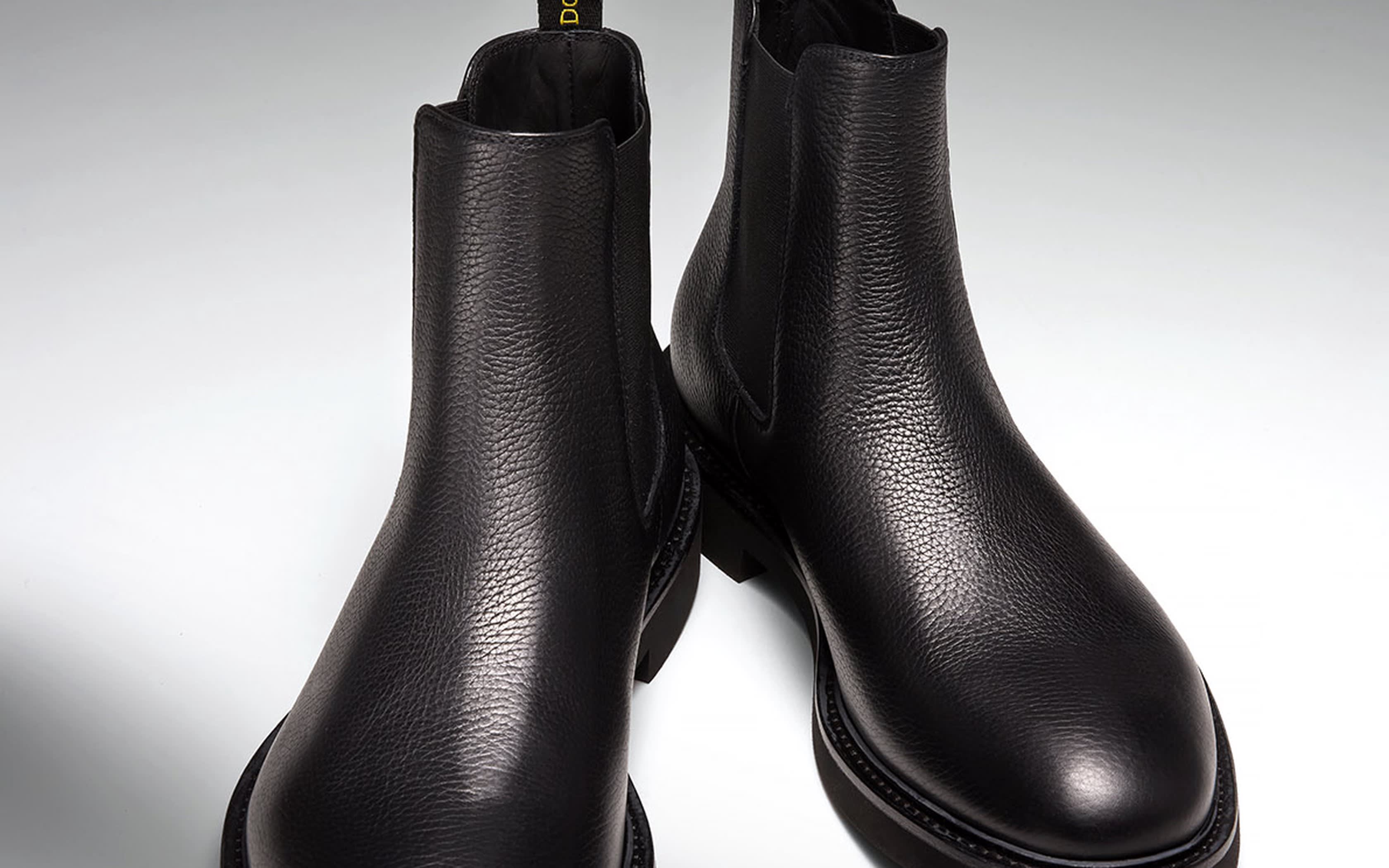 Schwarze Chelsea-Stiefel aus genarbtem Leder mit runder Kappe vor neutralem Hintergrund.