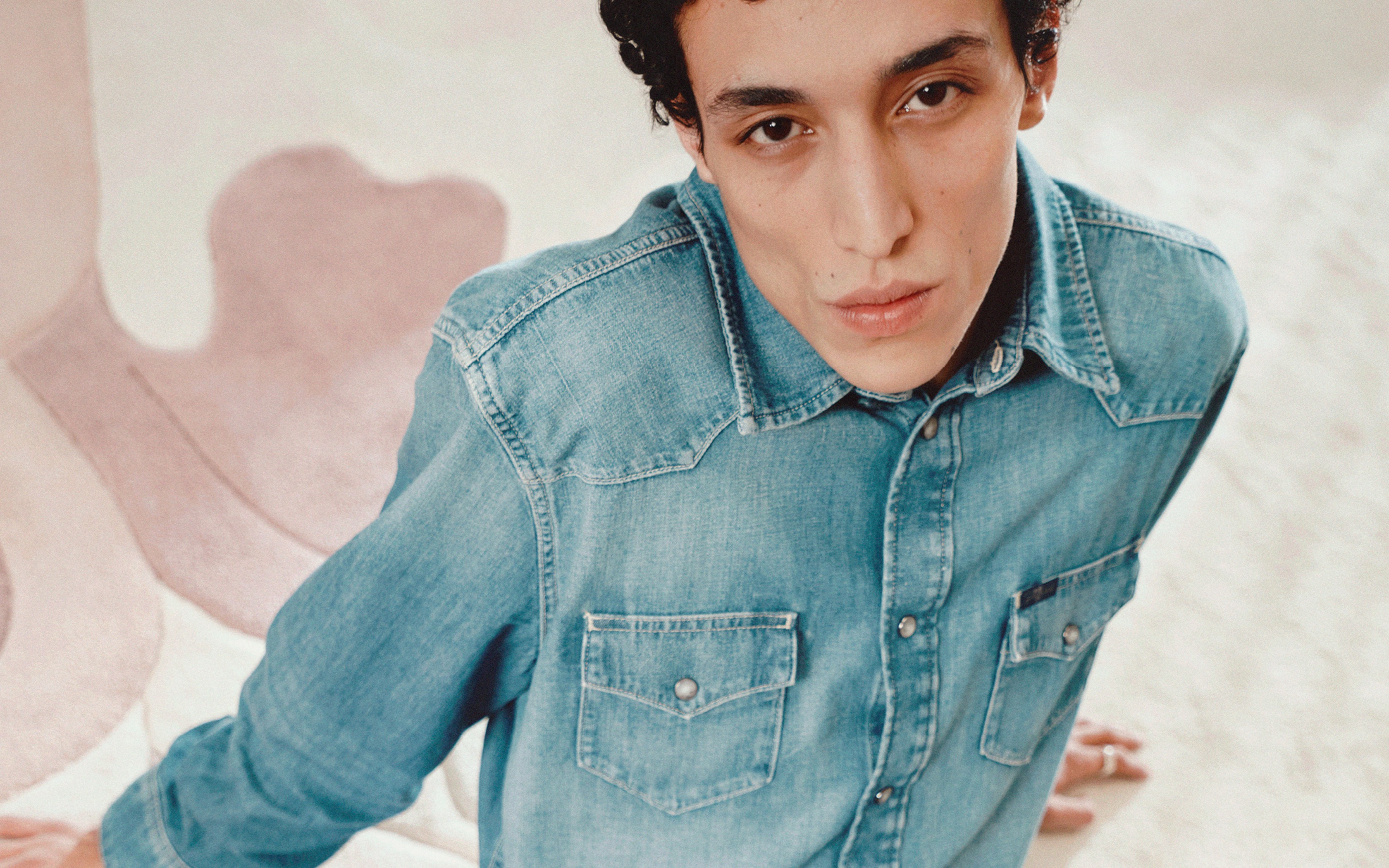 Un jeune homme en chemise en denim bleu clair.