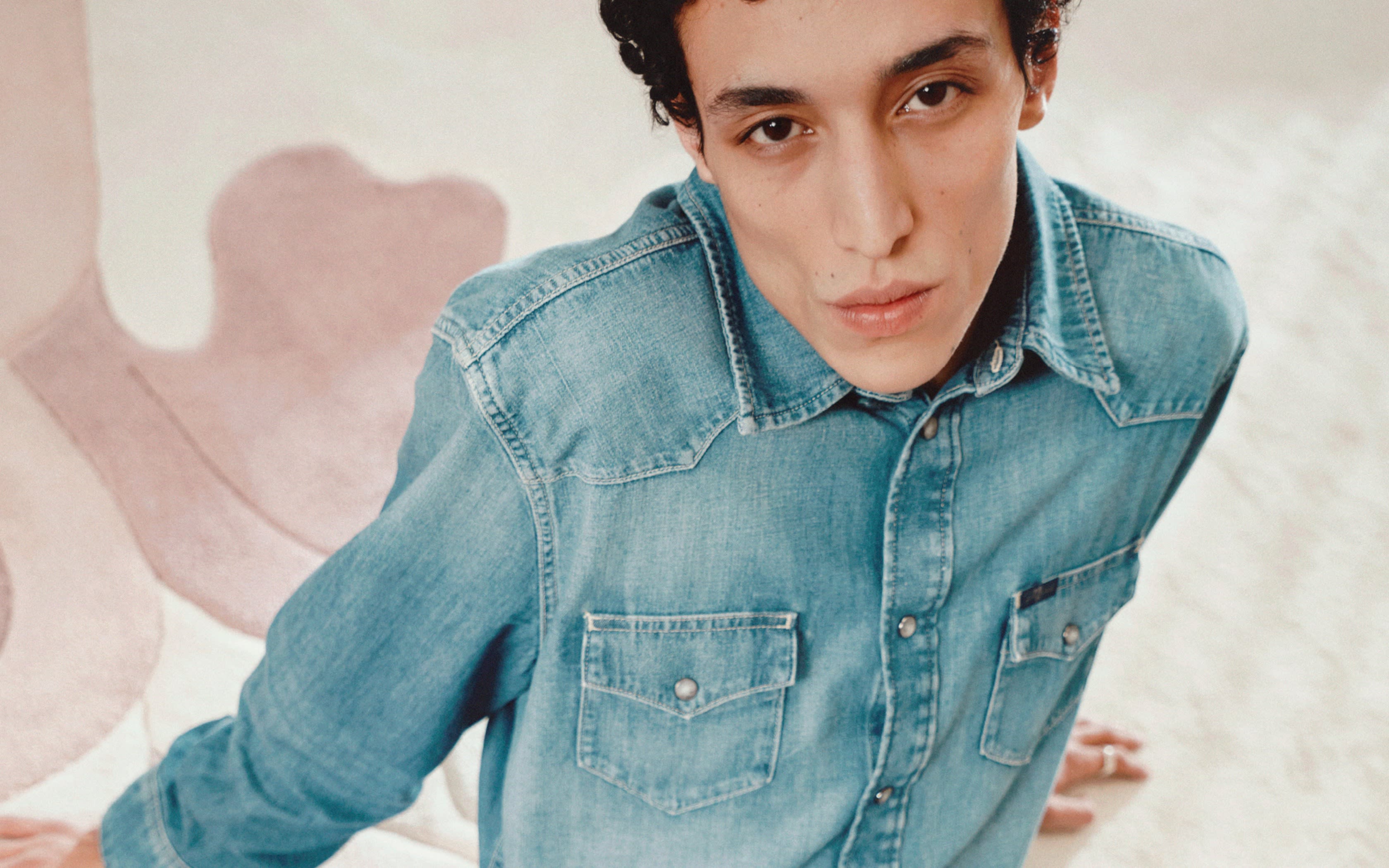 Un jeune homme en chemise en denim bleu clair.