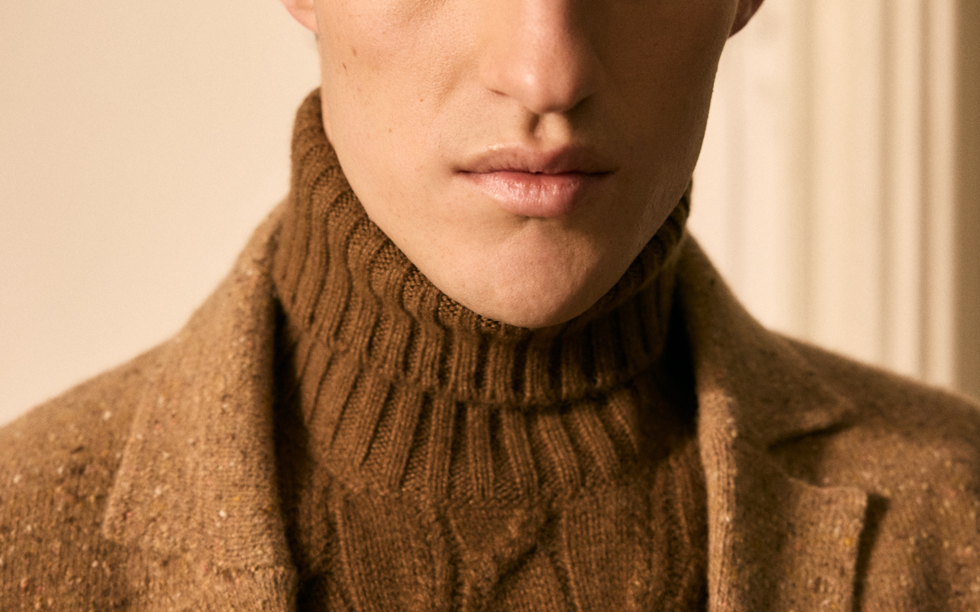 Porträt eines Mannes im braunen Wollmantel und Zopfmuster-Rollkragenpullover.